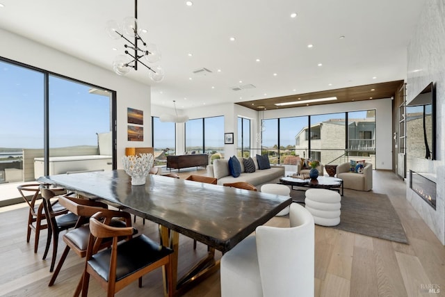 dining space featuring a notable chandelier, a large fireplace, light wood-style flooring, recessed lighting, and visible vents