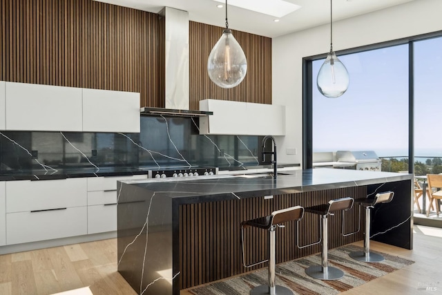 kitchen with dark countertops, modern cabinets, white cabinets, tasteful backsplash, and a sink