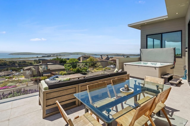 view of patio / terrace featuring outdoor dining area, a water view, and a hot tub