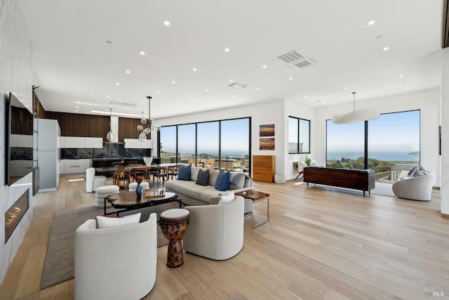 living room with recessed lighting, light wood-style flooring, and visible vents