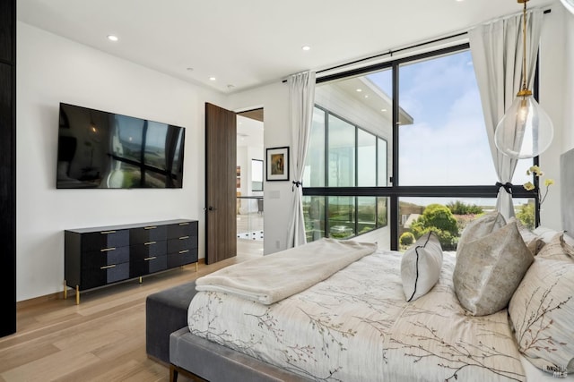 bedroom featuring light wood-type flooring, recessed lighting, and floor to ceiling windows
