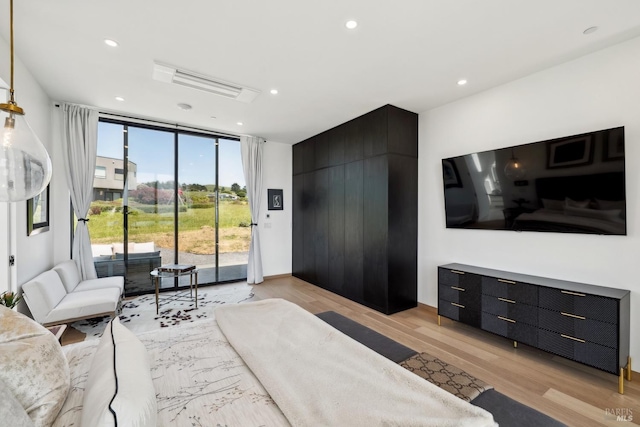 bedroom with access to outside, light wood-type flooring, recessed lighting, and a wall of windows