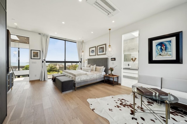 bedroom featuring ensuite bath, visible vents, expansive windows, light wood finished floors, and recessed lighting