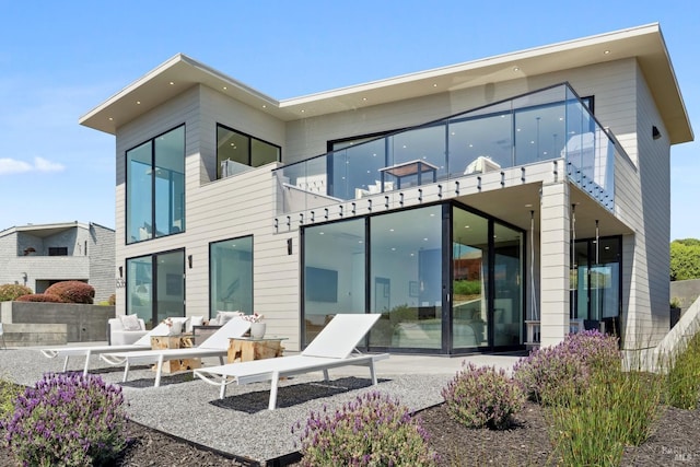 rear view of house featuring an outdoor living space, a balcony, and a patio area