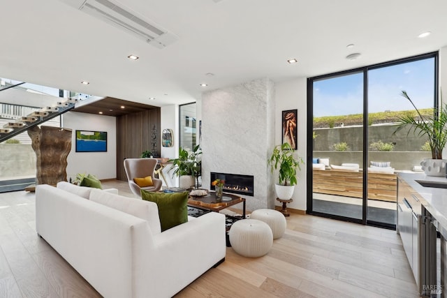 living area with wine cooler, light wood-style floors, recessed lighting, a large fireplace, and expansive windows