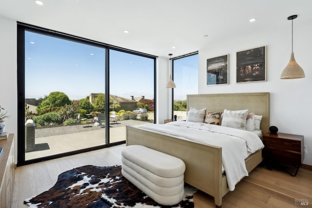 bedroom featuring access to outside, floor to ceiling windows, wood finished floors, and recessed lighting