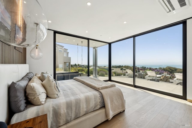 bedroom with access to outside, a wall of windows, recessed lighting, wood finished floors, and visible vents