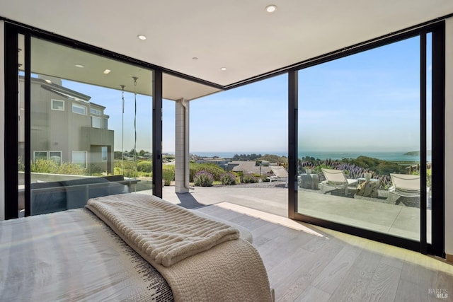 bedroom with floor to ceiling windows, recessed lighting, and wood finished floors