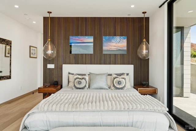 bedroom with recessed lighting, an accent wall, baseboards, and wood finished floors