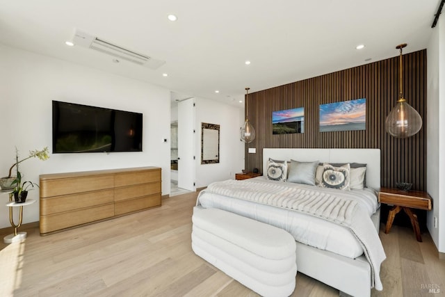 bedroom featuring recessed lighting, an accent wall, and light wood-style floors