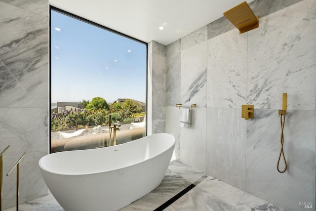 bathroom featuring recessed lighting, marble finish floor, a freestanding bath, and tile walls