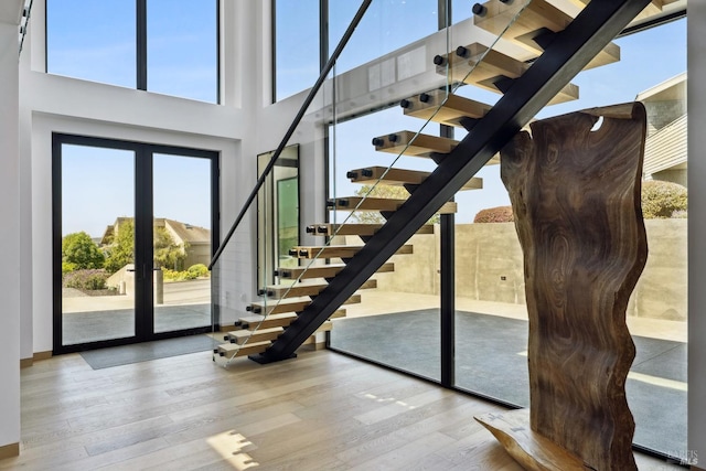 entryway featuring french doors, a high ceiling, wood finished floors, and stairway