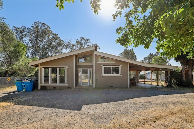 rear view of house featuring crawl space, driveway, fence, and an attached carport
