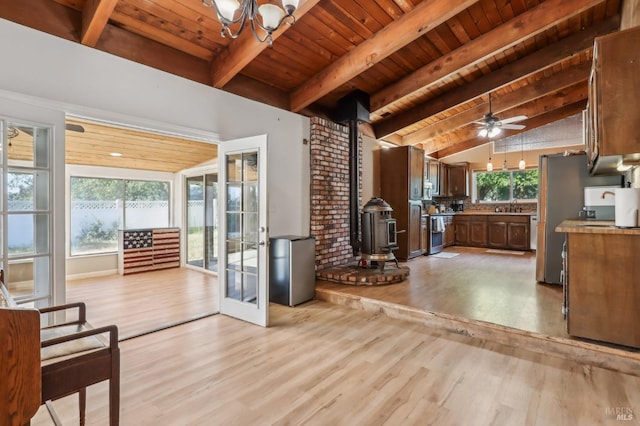 kitchen with a wood stove, wooden ceiling, light wood-style flooring, freestanding refrigerator, and backsplash