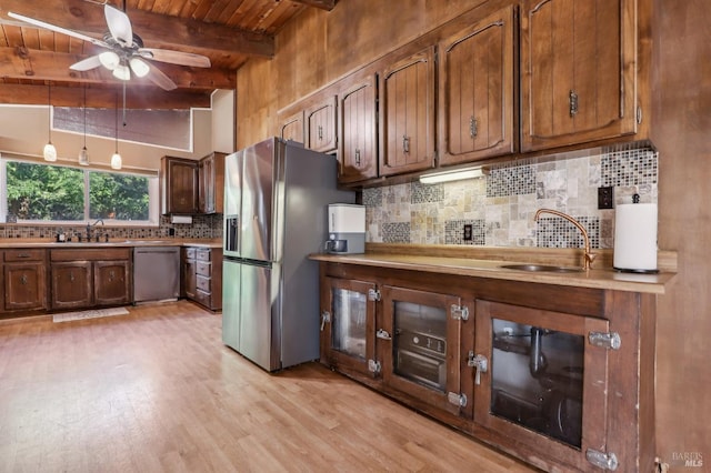 kitchen with stainless steel appliances, a sink, light wood finished floors, ceiling fan, and beamed ceiling