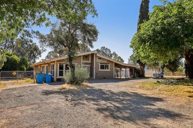view of front of property with fence and dirt driveway