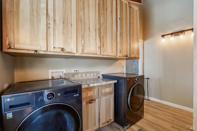 washroom featuring cabinet space, light wood-type flooring, baseboards, and washing machine and clothes dryer