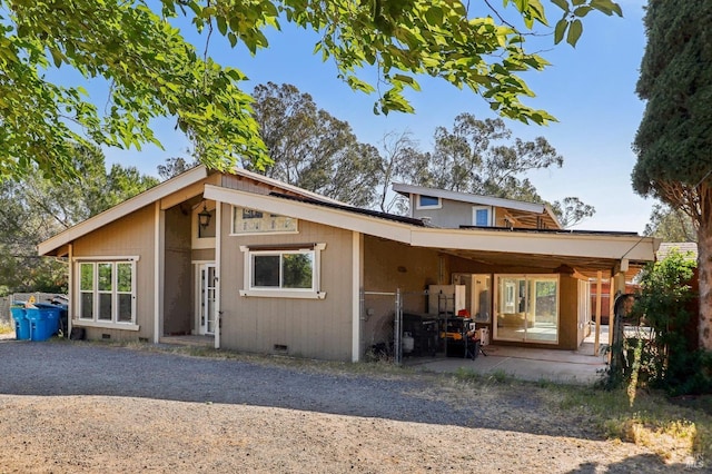 back of property featuring a patio area, crawl space, gravel driveway, and an attached carport