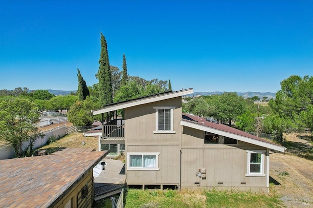 view of property exterior with a balcony and a mountain view