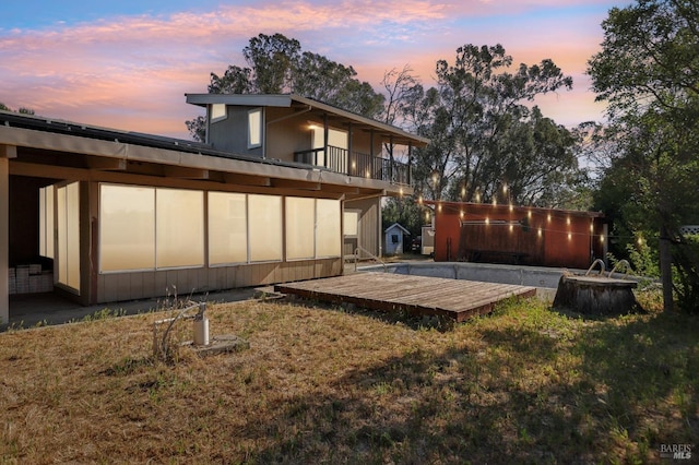 rear view of house featuring a wooden deck and a lawn