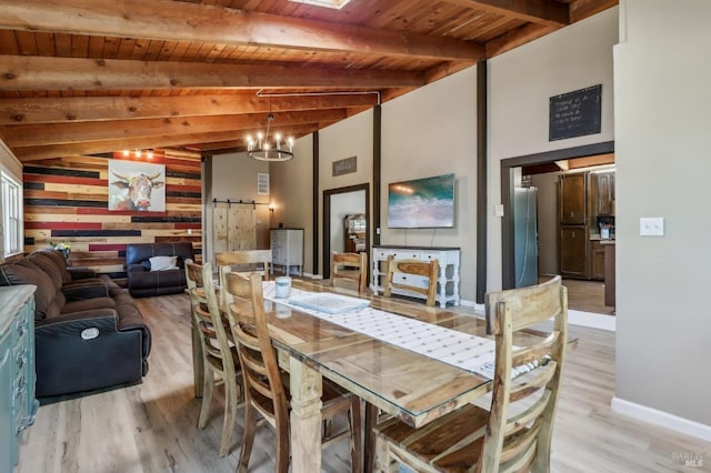 dining space with a barn door, light wood-style floors, wooden ceiling, baseboards, and beam ceiling