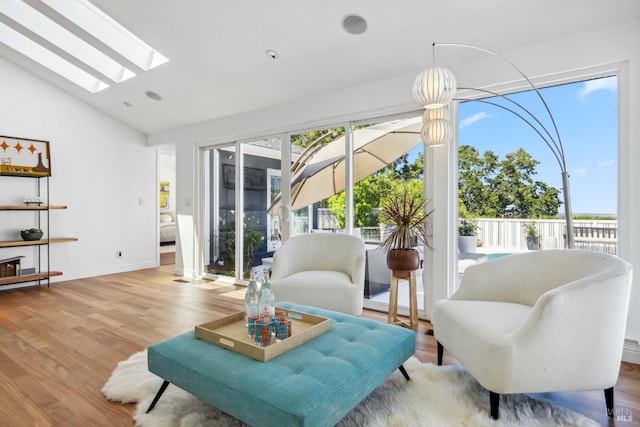 sitting room featuring baseboards, lofted ceiling with skylight, and wood finished floors