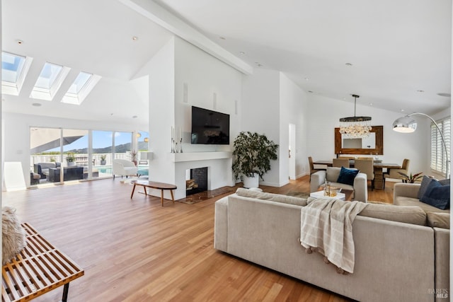 living room with high vaulted ceiling, an inviting chandelier, light wood-type flooring, and a fireplace