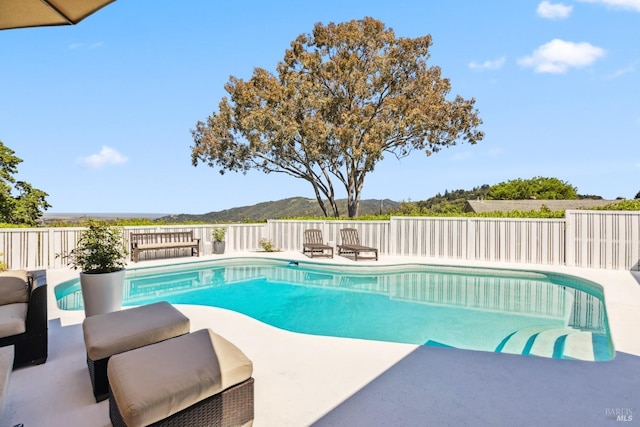 view of swimming pool with a fenced in pool, a mountain view, fence, and a patio area