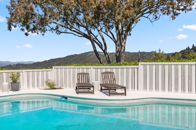 view of pool featuring fence, a fenced in pool, a mountain view, and a patio area