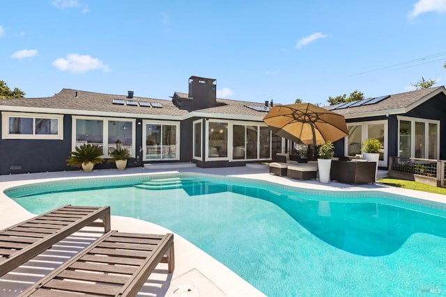 outdoor pool with a sunroom, a patio, and an outdoor living space