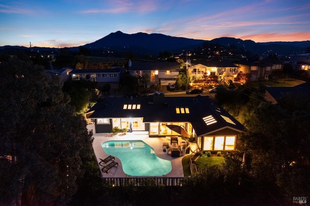 back of property at dusk featuring an outdoor hangout area, a mountain view, a patio area, and an outdoor pool