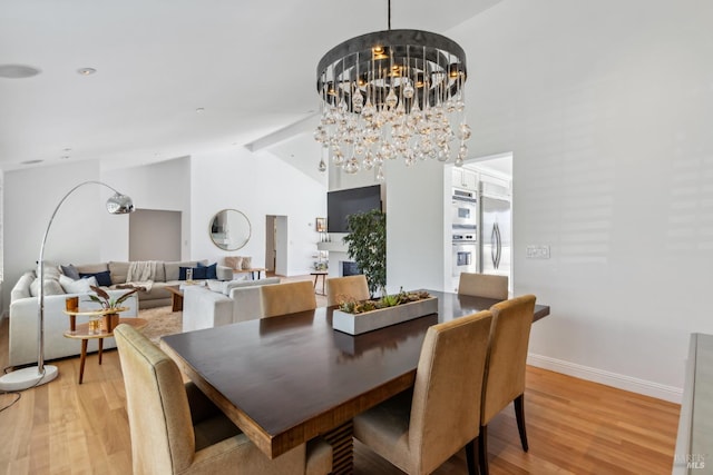 dining area featuring light wood-type flooring, baseboards, a chandelier, and vaulted ceiling