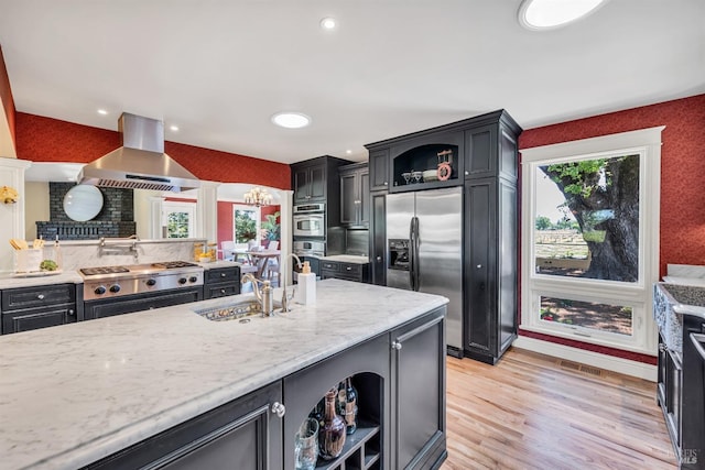 kitchen with exhaust hood, appliances with stainless steel finishes, open shelves, a sink, and light stone counters