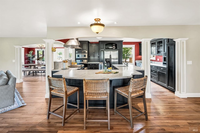 kitchen with a breakfast bar area, ornate columns, a sink, and stainless steel appliances