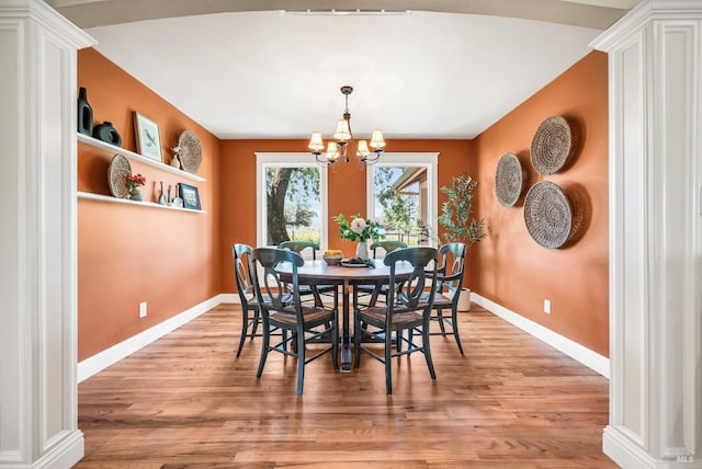 dining area with an inviting chandelier, light wood-style flooring, ornate columns, and baseboards
