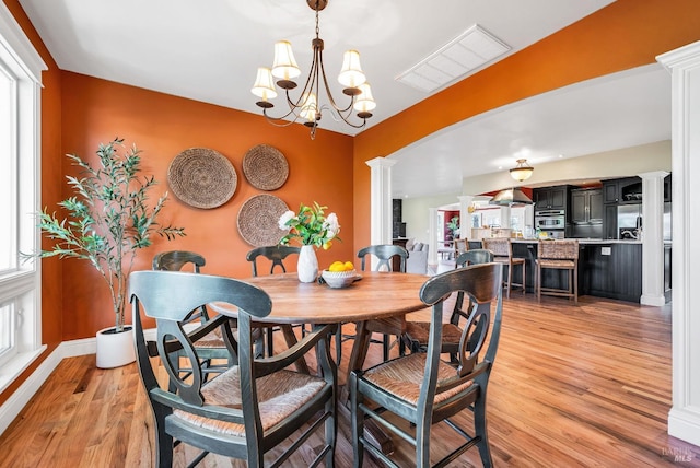 dining area with visible vents, plenty of natural light, ornate columns, and light wood-type flooring