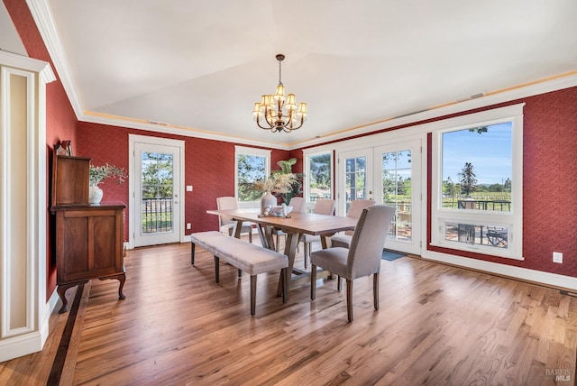 dining area featuring crown molding, wood finished floors, wallpapered walls, french doors, and a notable chandelier