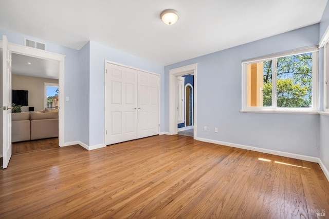 unfurnished bedroom with baseboards, a closet, light wood-type flooring, and visible vents