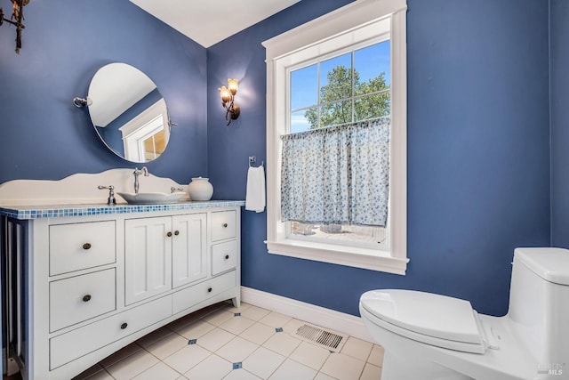 half bath with vanity, toilet, tile patterned floors, baseboards, and visible vents