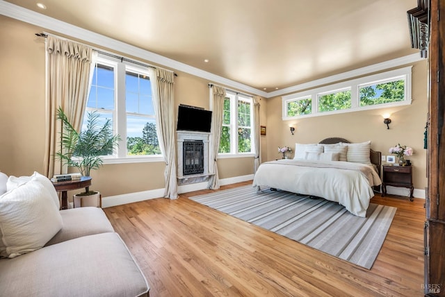 bedroom with baseboards, ornamental molding, and light wood-type flooring
