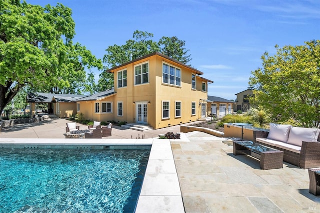 back of house featuring french doors, an outdoor living space with a fire pit, a patio area, and an outdoor pool