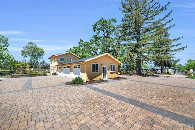 view of front facade with an attached garage, decorative driveway, and stucco siding