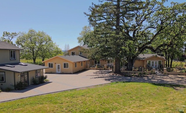 back of property with french doors, stucco siding, a yard, and driveway