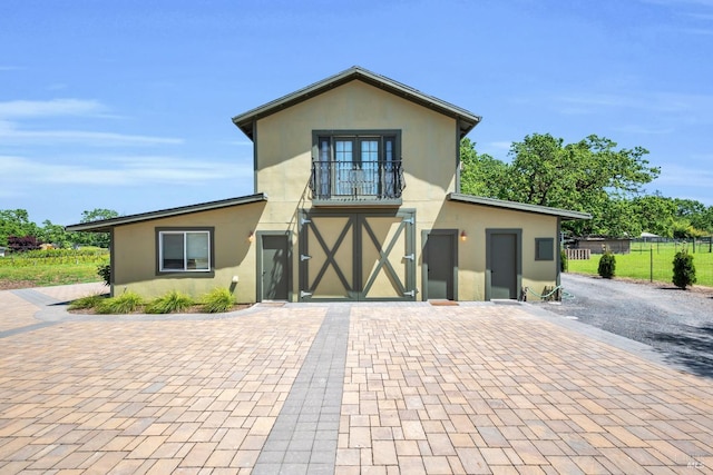 view of front of home featuring decorative driveway, fence, a balcony, an attached garage, and stucco siding