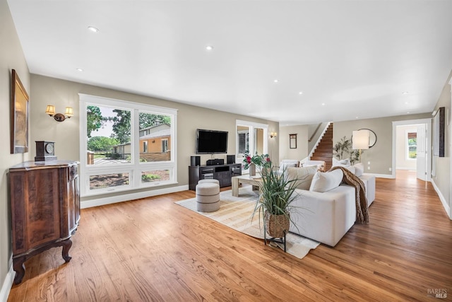 living room with stairs, baseboards, a wealth of natural light, and wood finished floors