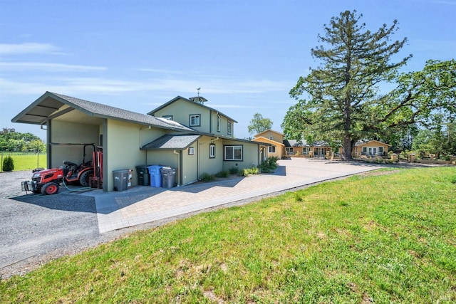 back of house featuring a lawn, stucco siding, and a carport