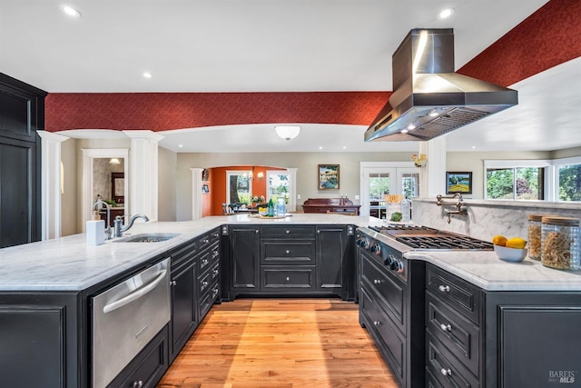 kitchen featuring decorative columns, a sink, light wood-style floors, a warming drawer, and extractor fan