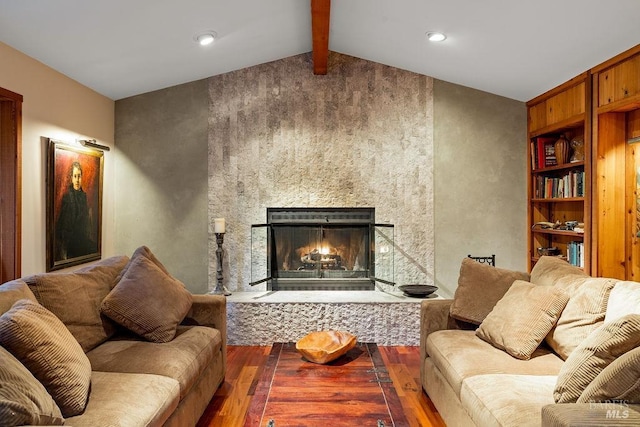 living room featuring lofted ceiling with beams, wood finished floors, and a large fireplace