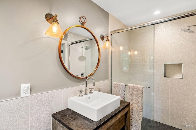 bathroom featuring a sink, tile walls, a wainscoted wall, and an enclosed shower