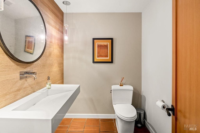 bathroom featuring baseboards, a sink, tile patterned flooring, and toilet
